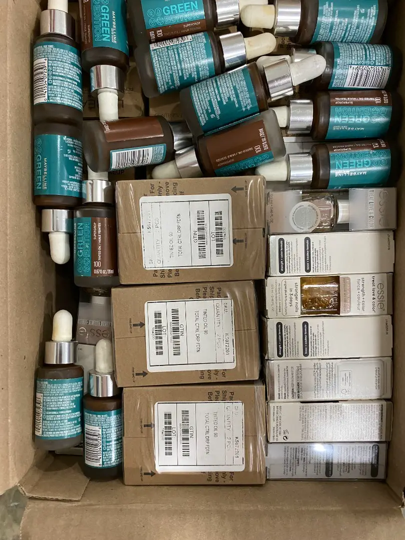 Maybelline Green Edition boxes and Essie nail polish bottles in a wholesale case